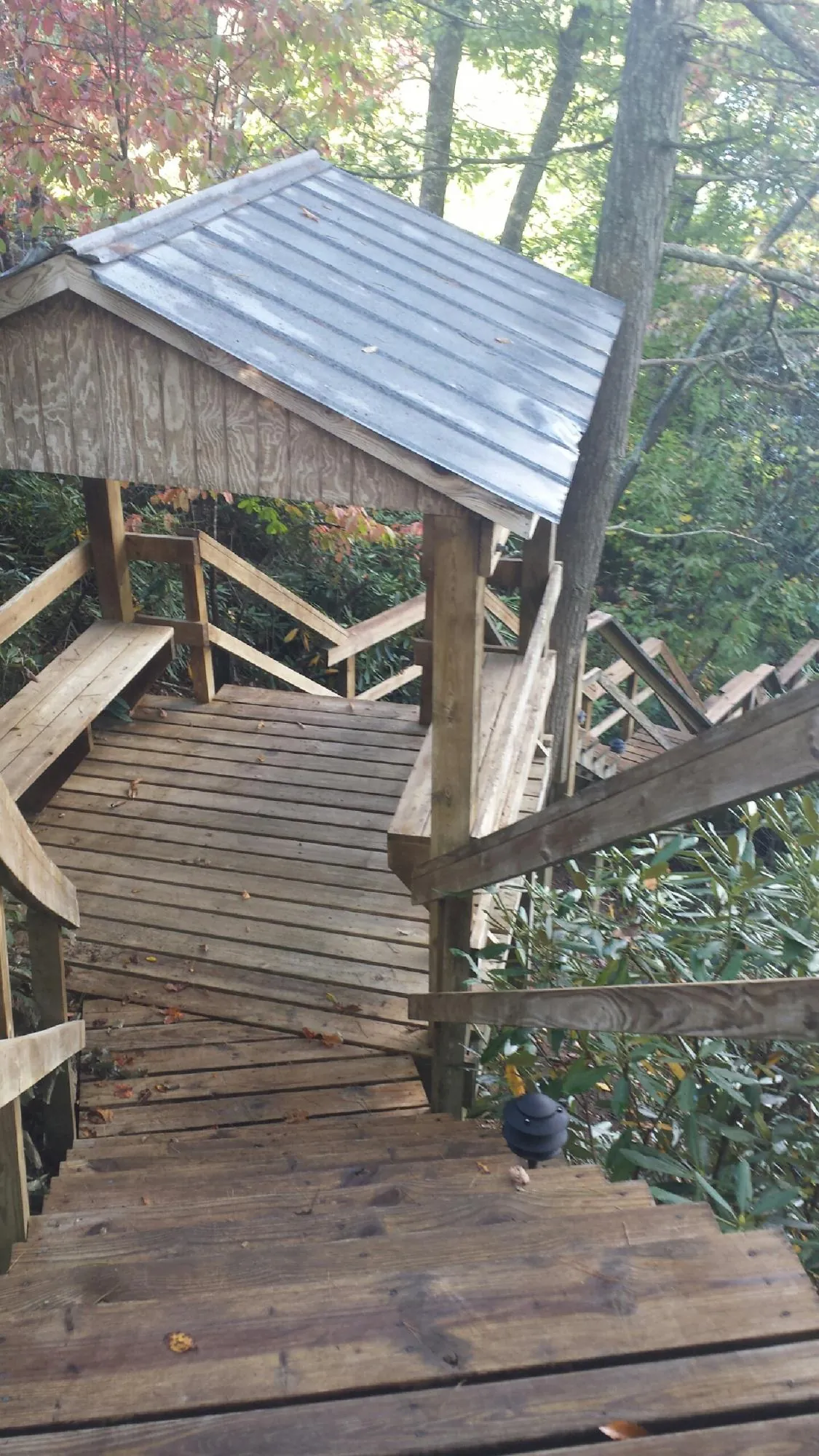 Metal roofed shelter over wooden steps on a wooded walkway — Skylight Repair & Installation work by our crew in Burnsville