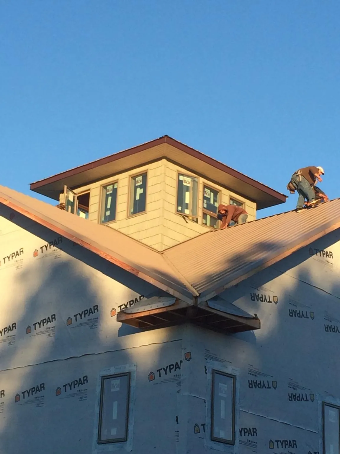 Roofers working around a rooftop cupola on a new metal roof at sunset — Roof Waterproofing in Burnsville by Roofing Brothers